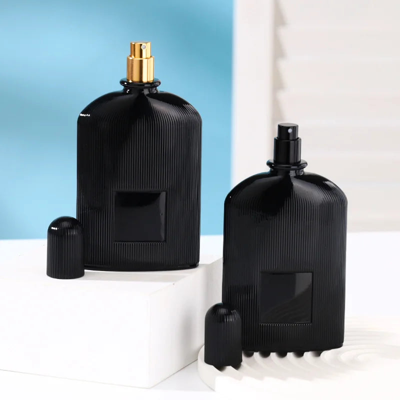 2 black perfume bottles, one with a gold spray head, one with a black spray head