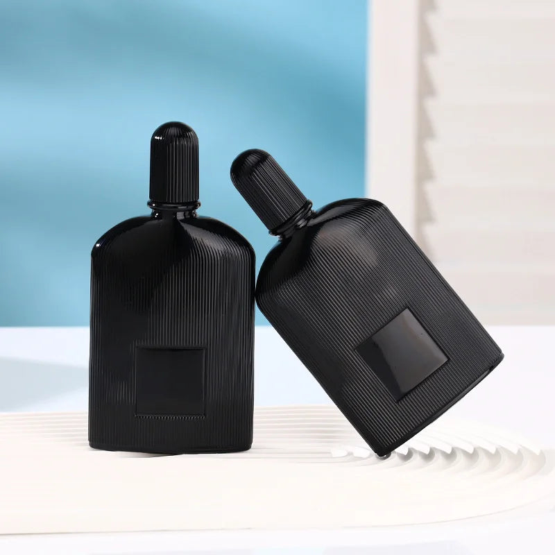 2 black perfume bottles, one leaning on top of the other