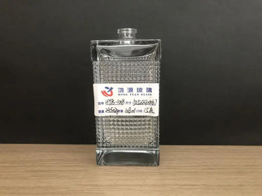 A flat rectangular perfume bottle with a regular small square pattern designed in the center of the bottle, forming a ribbon around the bottle.
