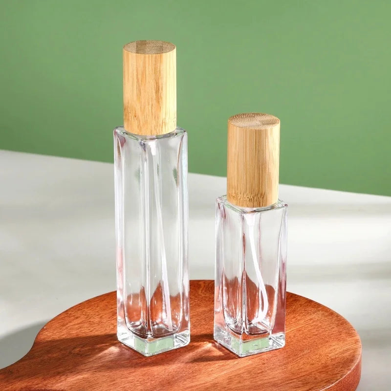 2 slim rectangular glass perfume bottles of different capacities with cylindrical caps made of bamboo