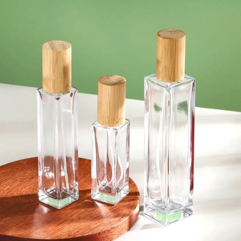 3 slim rectangular glass perfume bottles of different capacities with cylindrical caps made of bamboo