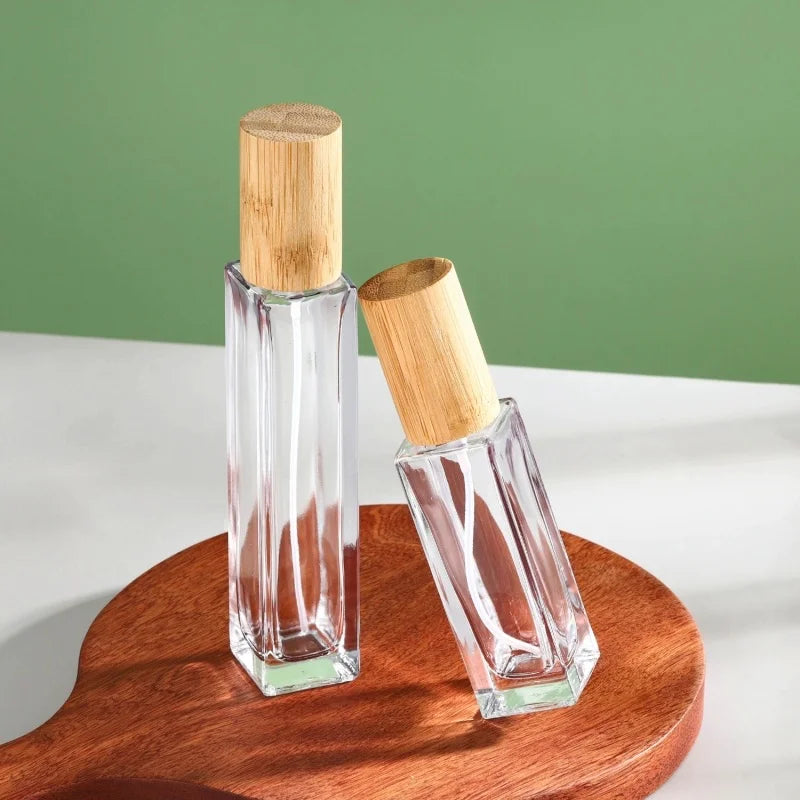 2 slim rectangular glass perfume bottles of different capacities with cylindrical caps made of bamboo