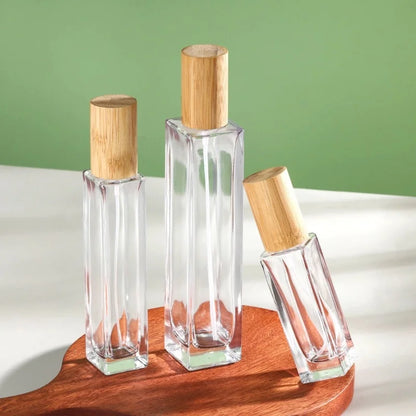 3 slim rectangular glass perfume bottles of different capacities with cylindrical caps made of bamboo